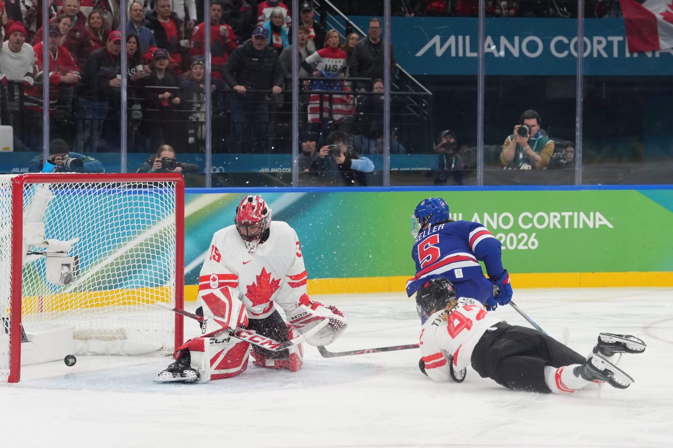 Megan Keller, in a blue United States jersey, watches as the puck gets past Canada goalkeeper Ann-Renée Desbiens for the winning goal.