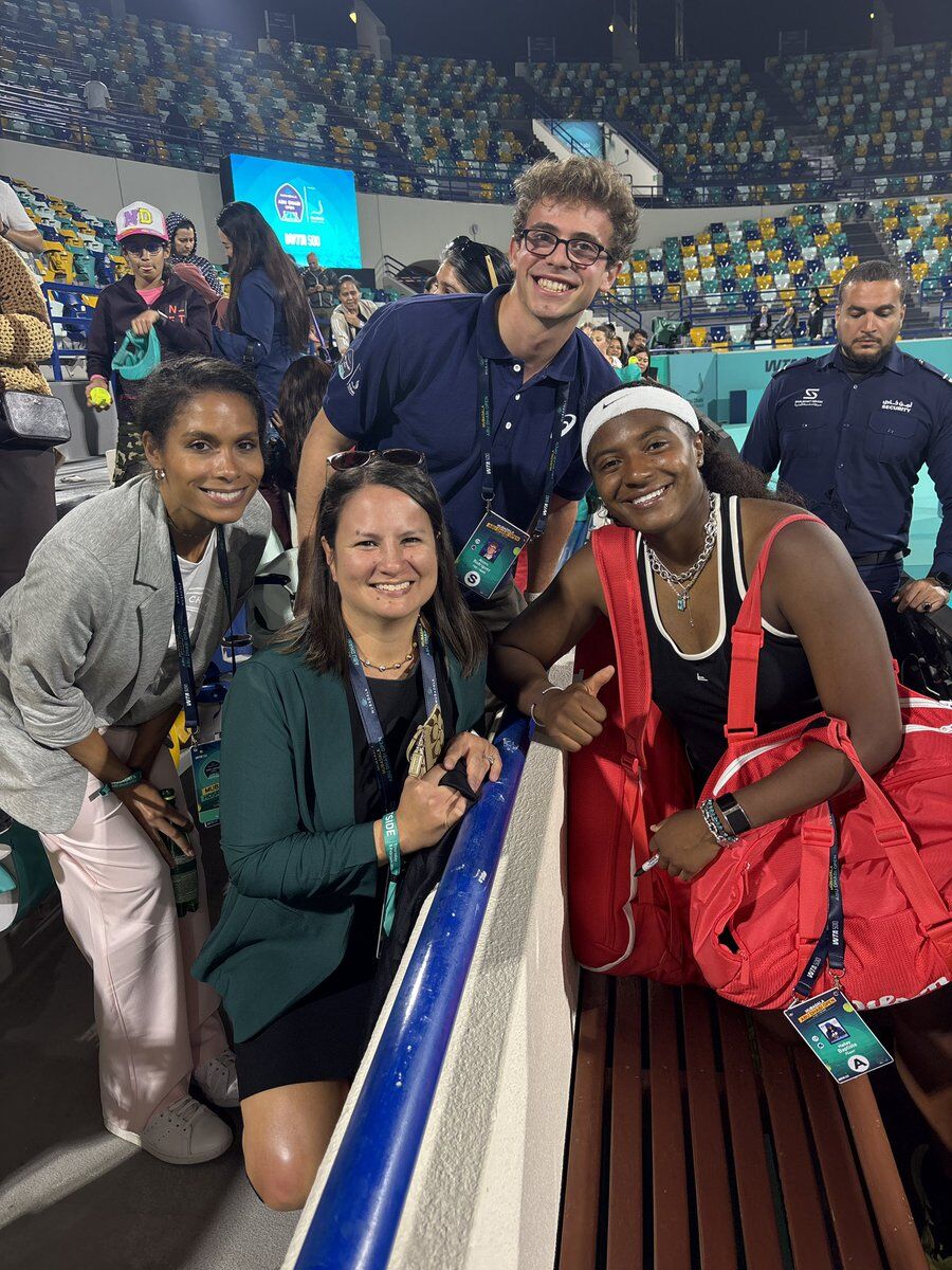 tennis player on right posing for picture with members of crowd on left