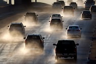 Spray from melting sleet and ice is kicked up on Interstate 30 in Arlington as drivers...