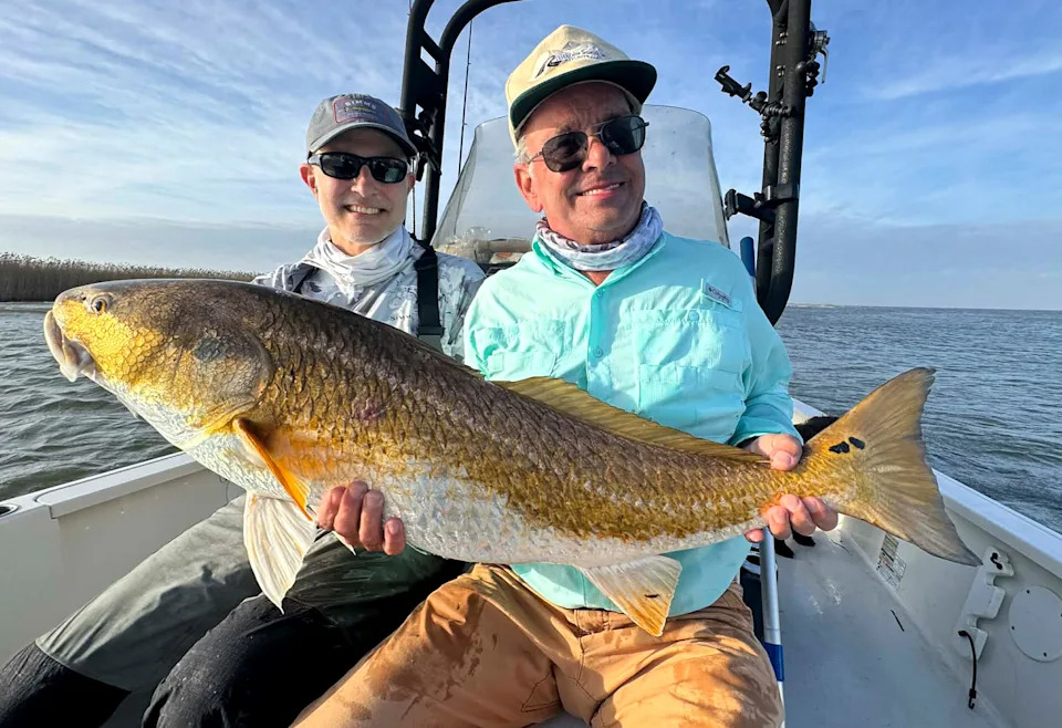 Two visiting anglers with a big Louisiana redfish.