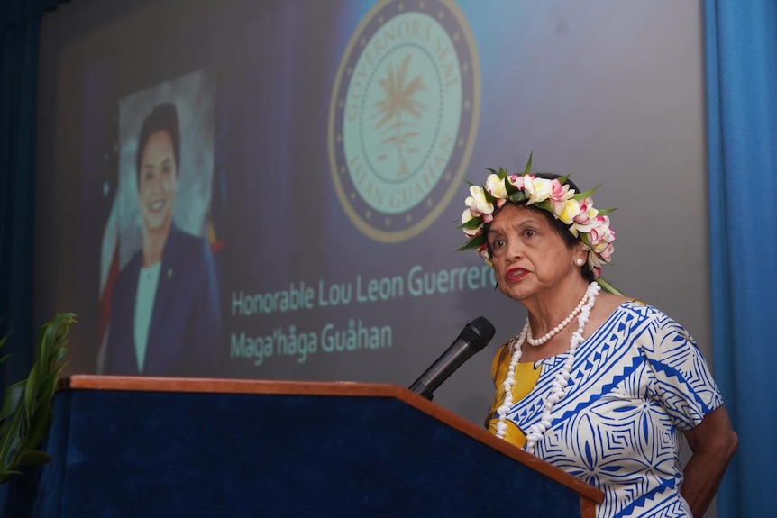 Guam woman wearing blue and white pacific top with shell necklace and floral headpiece