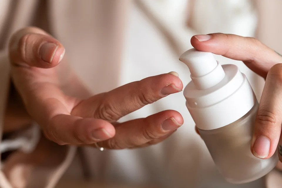 Person applying lotion from a small pump bottle onto their finger