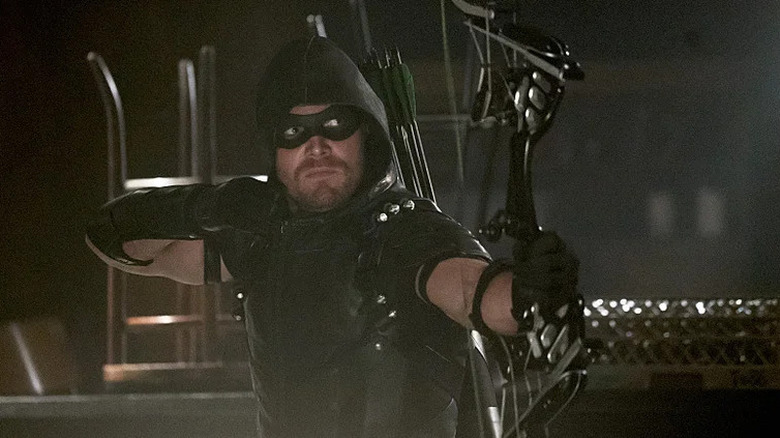 Oliver Queen wearing his vigilante costume and aiming his bow on Arrow (2012-2020)