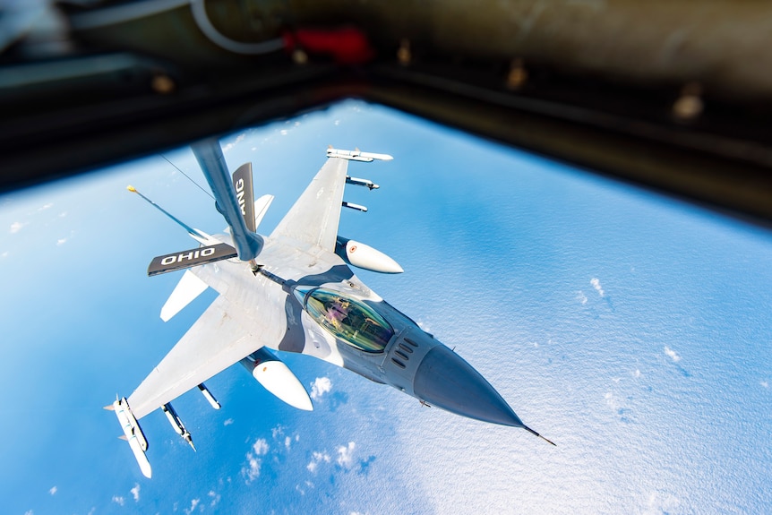 A jet being refuelled in the sky 