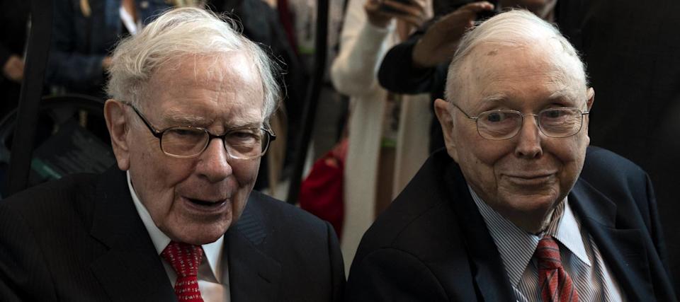Warren Buffett and Charlie Munger sit next to each other in black suits with red ties.
