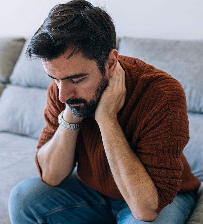 Man in a brown sweater sitting on a couch looking thoughtful among weirdly hilarious images to improve your mood.