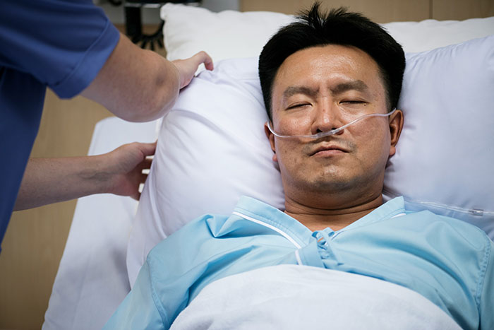 Man in hospital bed with oxygen tube, appearing serious and resting, fitting the weirdly hilarious images theme.