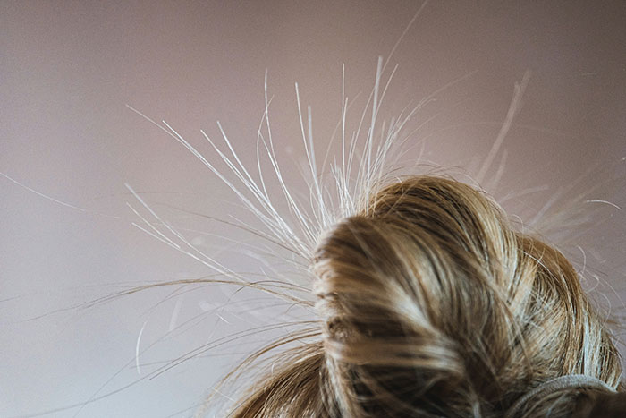 Close-up of static hair strands sticking out from a messy bun, a weirdly hilarious moment captured to improve your feed.