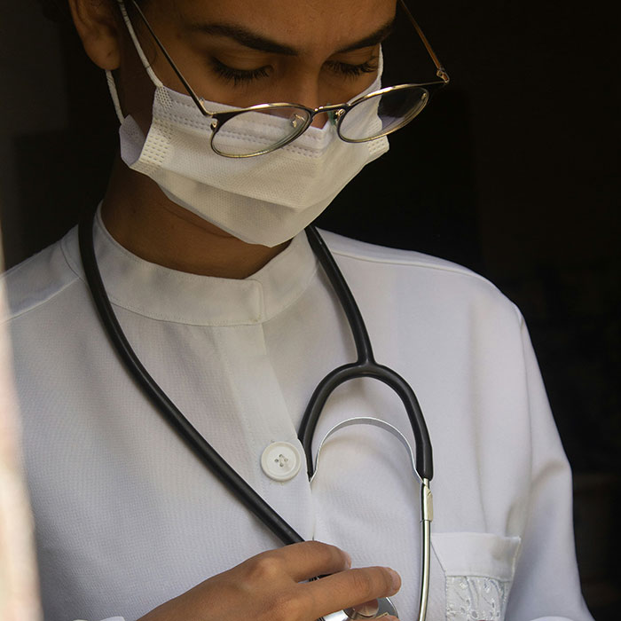 Healthcare professional wearing glasses and mask, focused on stethoscope, adding weirdly hilarious images to improve feed and mood