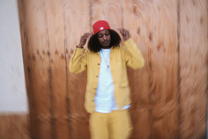 Man in red cap and yellow outfit standing against wooden background in a weirdly hilarious image to improve your feed and mood