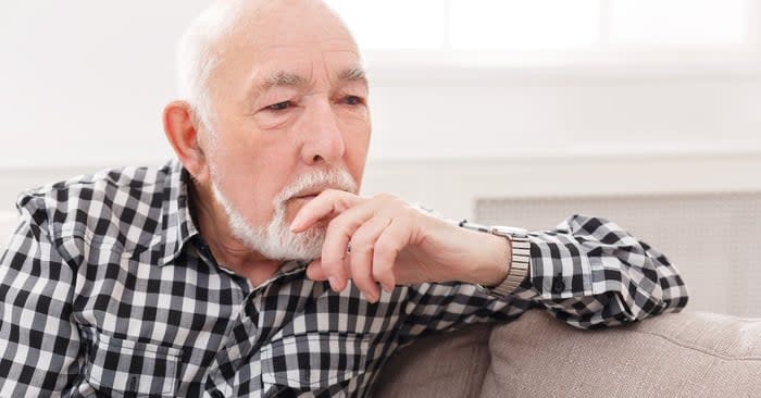 Pensive elderly man on sofa.
