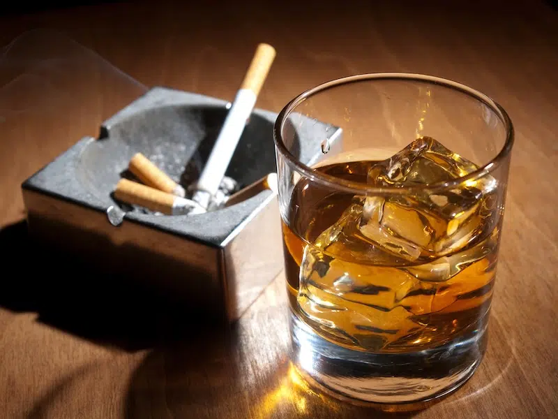 Smoking and drinking represented by cigarettes in an ashtray and a tumbler of scotch