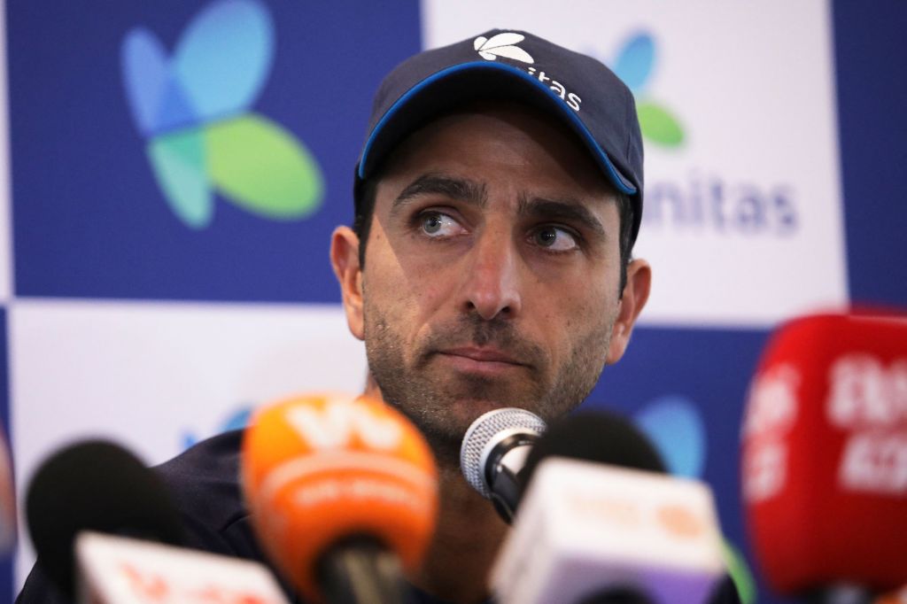 Tennis player Robert Farah sits in front of microphones at a press conference.