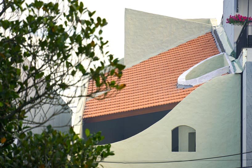 curved cutouts sculpt fluid voids within gabled residence in vietnam