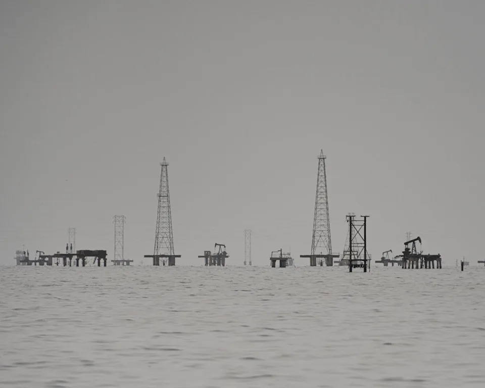 deteriorated oil rigs with towers, oil pumpjacks and gas flow stations