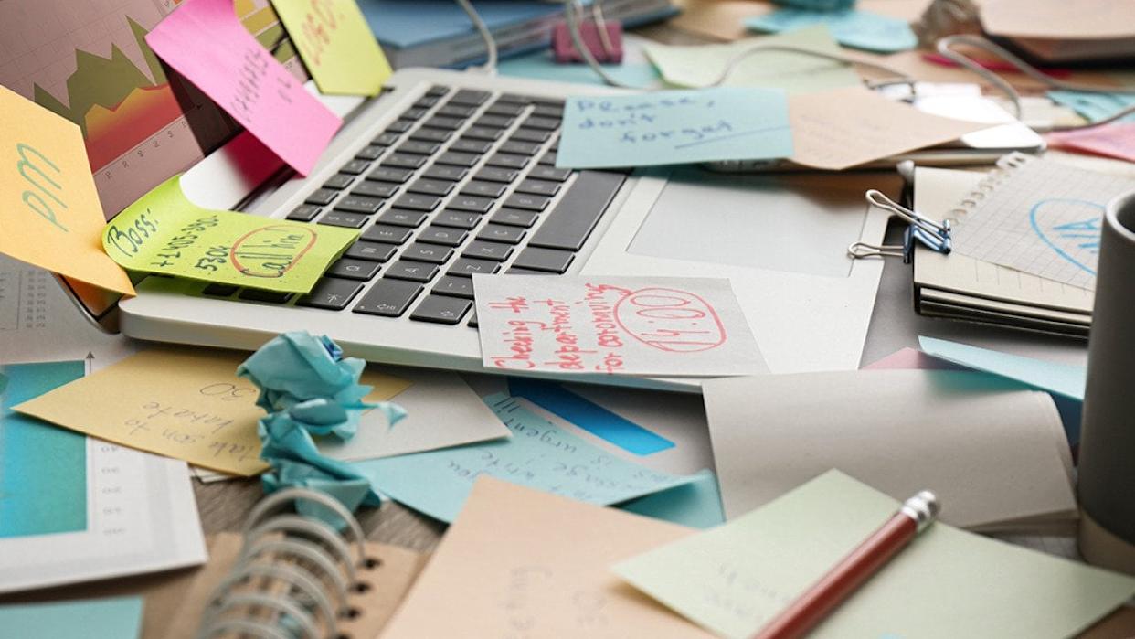 Sticky notes mess on top of a laptop on a working desk. - New Africa // Shutterstock