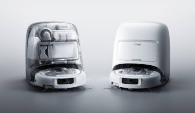 Two white robotic vacuum cleaners are shown side by side; one has its top open to reveal internal components and storage, while the other is closed, both set against a plain light background.