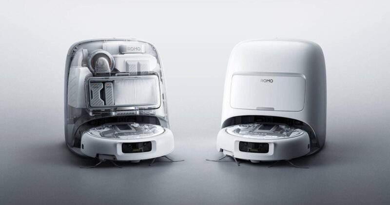 Two white robotic vacuum cleaners are shown side by side; one has its top open to reveal internal components and storage, while the other is closed, both set against a plain light background.