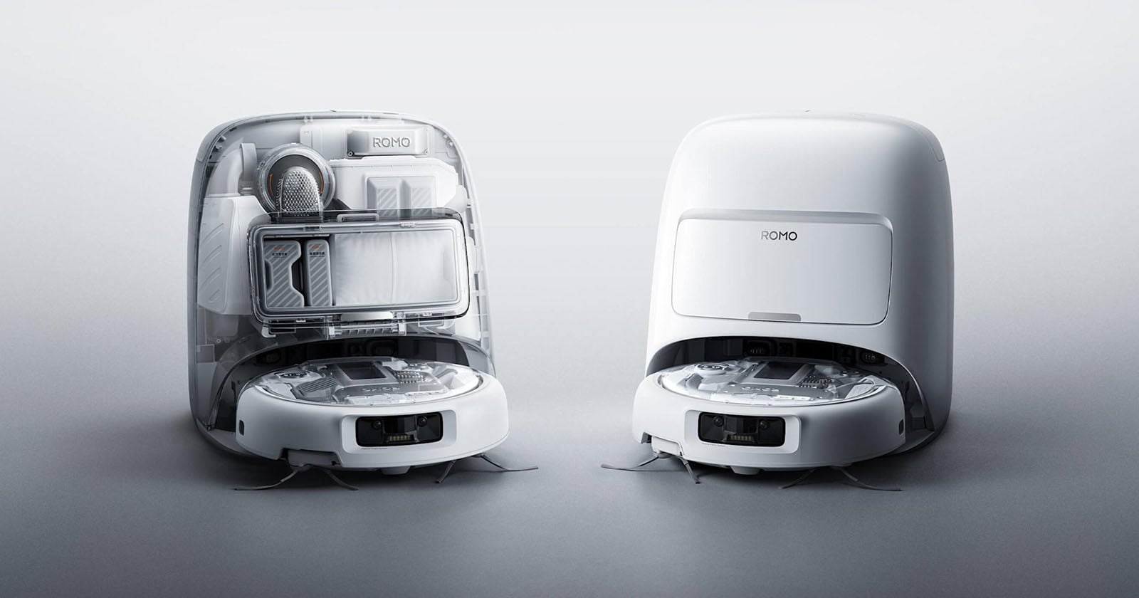 Two white robotic vacuum cleaners are shown side by side; one has its top open to reveal internal components and storage, while the other is closed, both set against a plain light background.