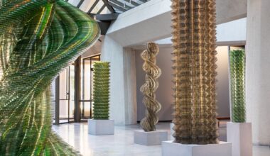 An installation view of towering artworks by Tara Donovan made of thousands of stacked CDs.