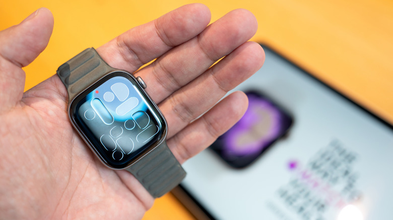 An Apple Watch with a red dot (Notifications Indicator) visible at the top of the screen.