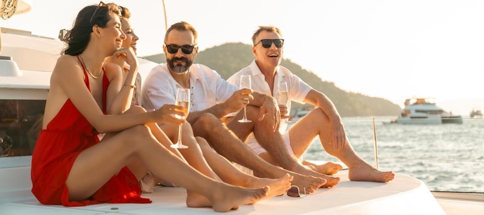 Four people celebrating on a yacht, drinking champagne.