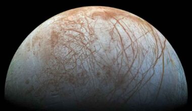 Europa, Jupiter’s icy ocean moon, showing a bright cracked surface with reddish-brown streaks against black space.