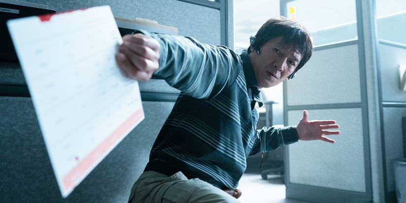 Ke Huy Quan as Waymond Wang mid-fight in an office building in Everything Everywhere All at Once.