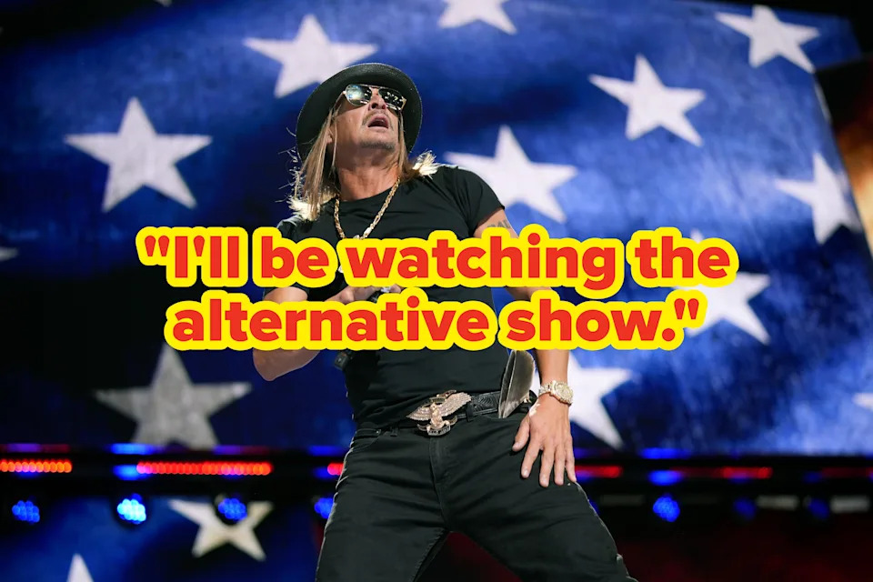 Kid Rock performing on stage, wearing a hat and sunglasses, with an American flag backdrop