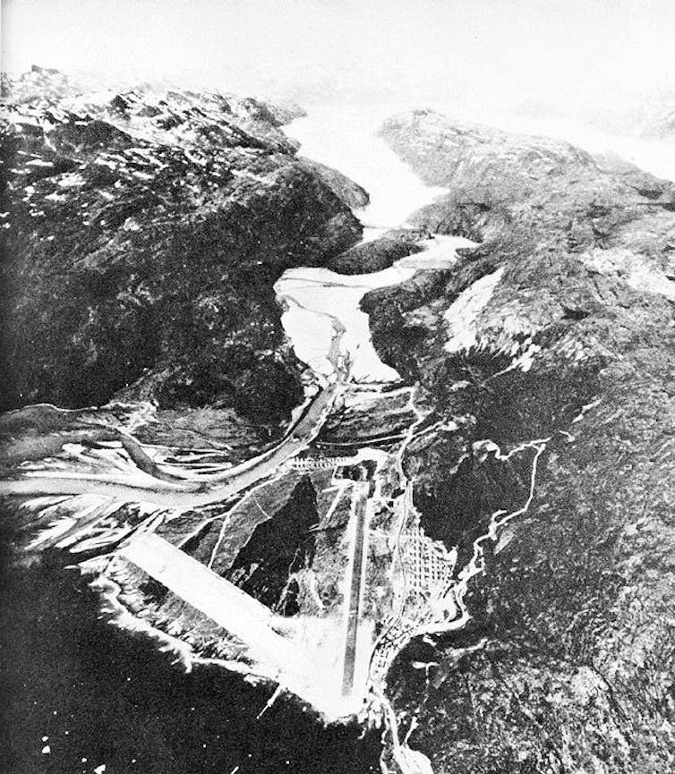 A photo from a plane of an airbase surrounded by mountains with glaciers above – in June.
