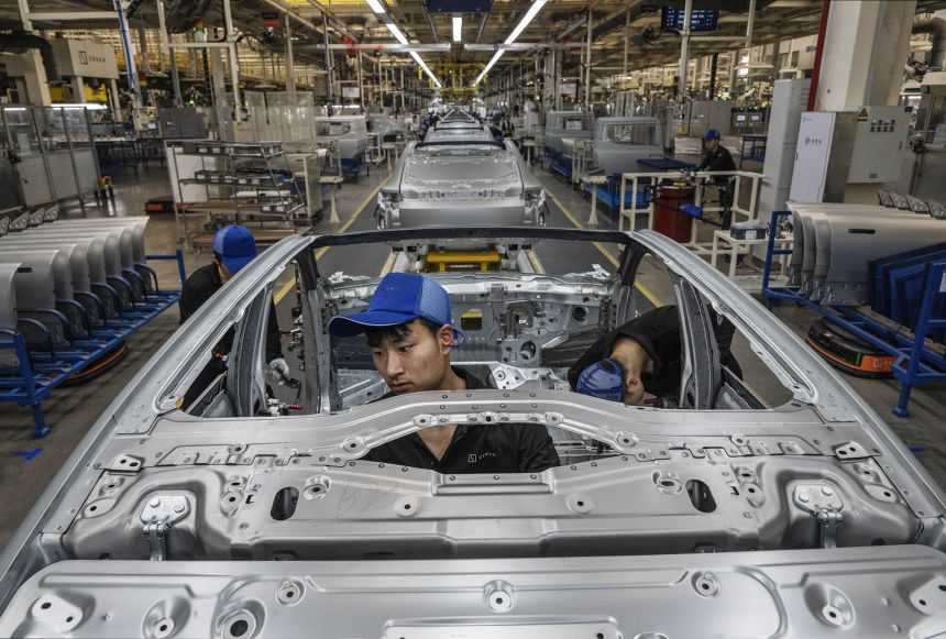 Workers in China assemble a car frame for electric vehicle maker Zeekr, whose plans to enter the US market has faced hurdles due to tariffs. Zeekr is owned by Geely Holdings, which has ownership stake in foreign brands like Volvo.