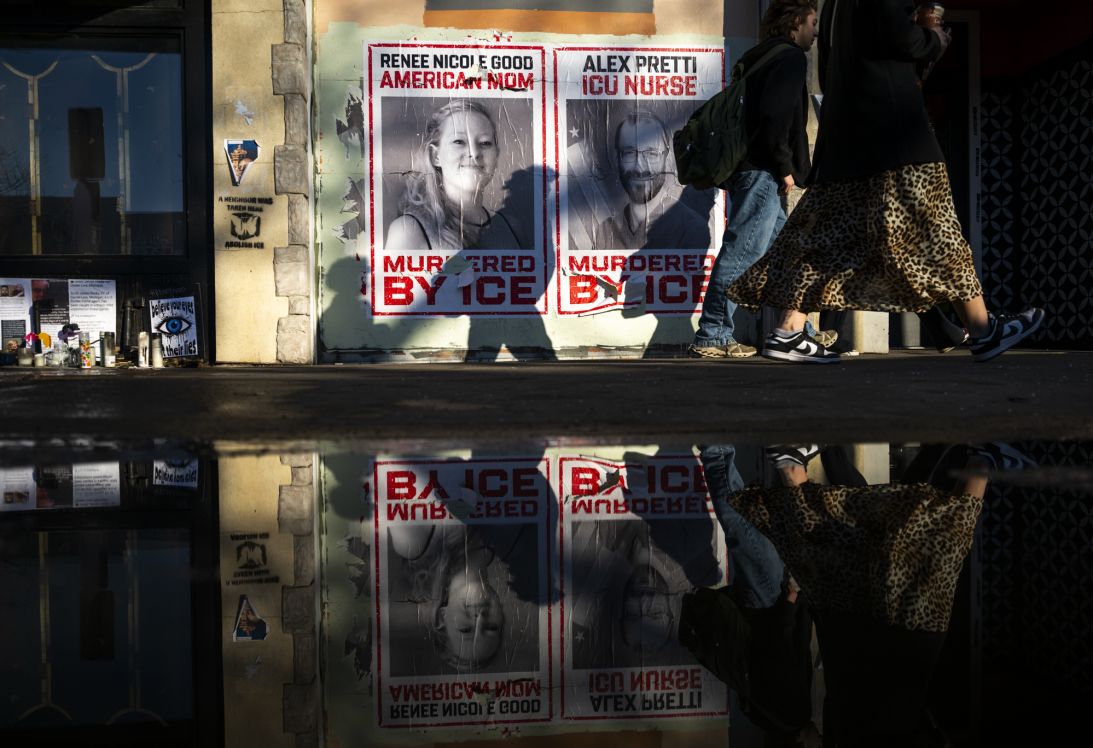 People walk by signs memorializing Renee Good and Alex Pretti on February 12, 2026 in Minneapolis, Minnesota.