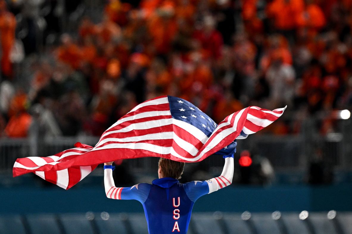 Team USA’s Jordan Stolz celebrates with the American flag after winning gold and setting an Olympic record in 500m speed skating on February 14..