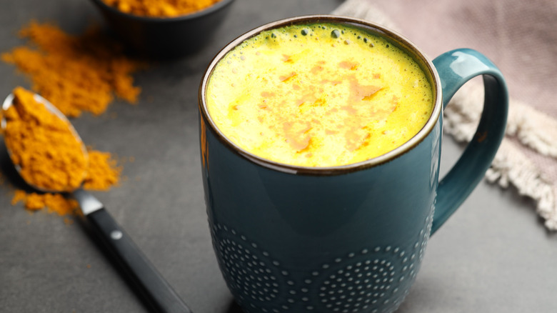 A cup of gold colored milk in a mug