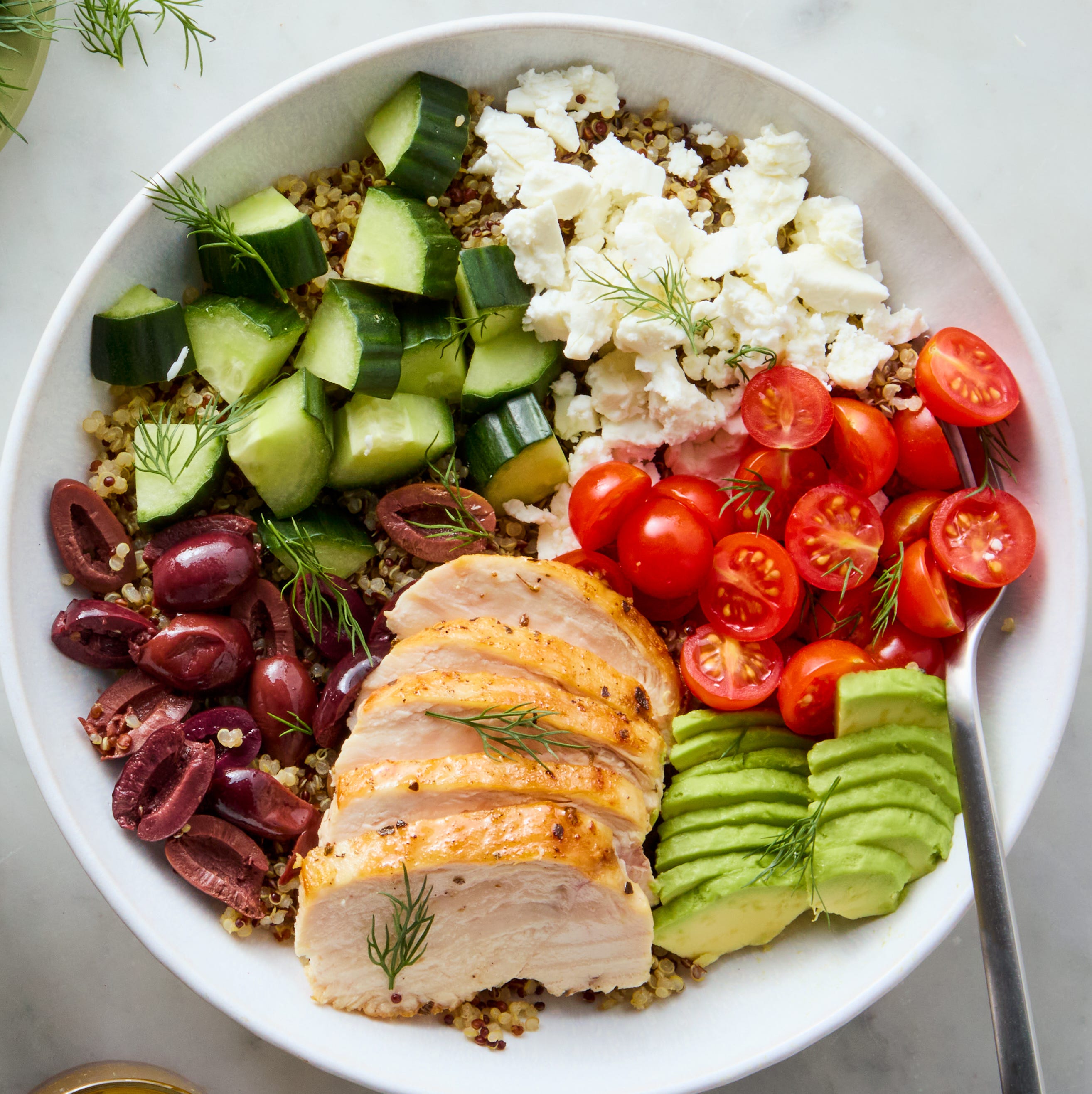 bowls filled with chicken, tomatoes, cucumber, olives, feta, and avocado