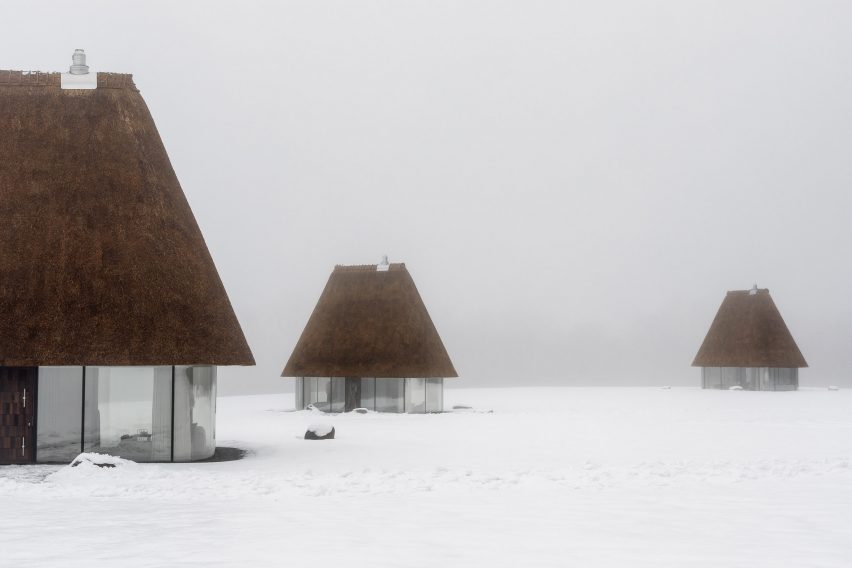 Glass hut with thatched roof in snowy landscape