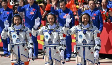A photo of three Chinese astronauts waving to the cameras before launching to space