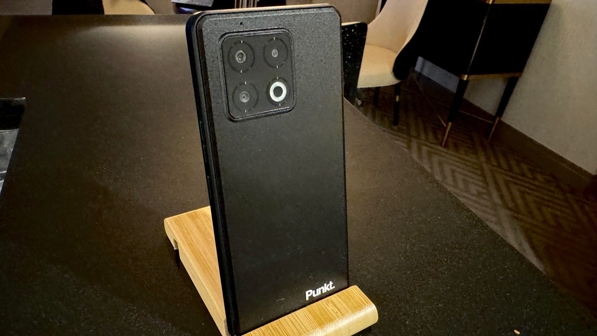 A black smartphone with "Punkt" inscribed in the lower-right corner rests in a wooden stand.