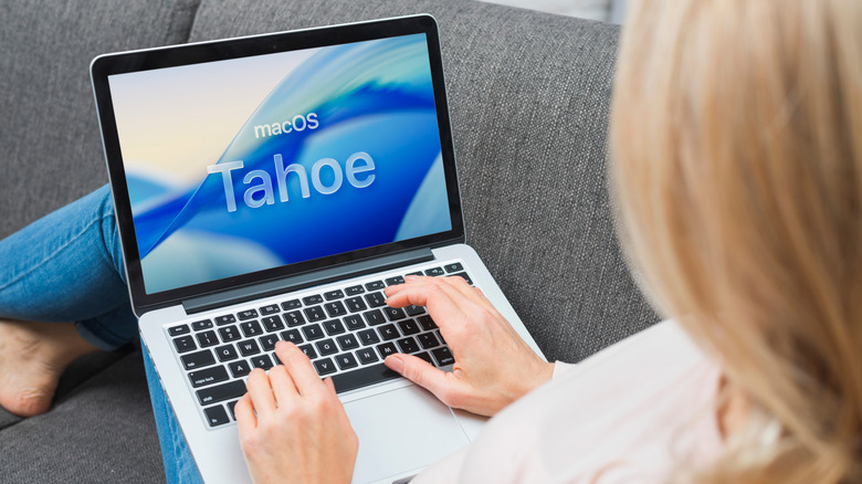 A person typing on a Mac with macOS Tahoe logo on the display