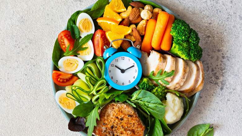 Different foods surrounded by blue analog clock in a bowl