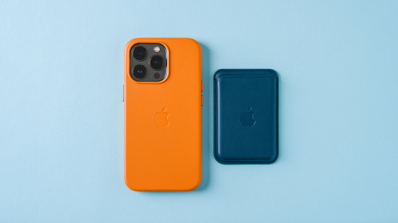 An iPhone 7 in orange beside a blue Apple MagSafe wallet