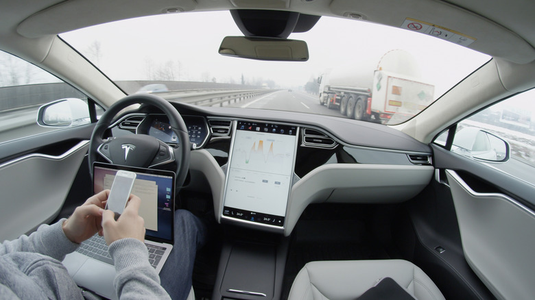 2017: Self-driving Tesla Model S car autopilot demanding driver attention to hold steering wheel take control on highway.