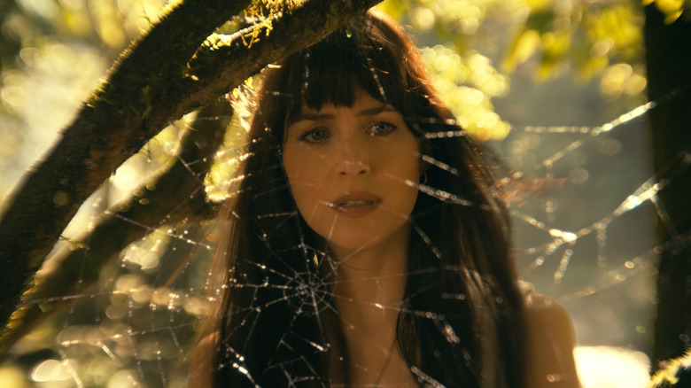 Dakota Johnson as Cassandra Webb lookiing at a spider web in Madame Web