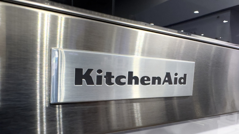 A close-up of a KitchenAid logo on a stainless steel appliance in a store