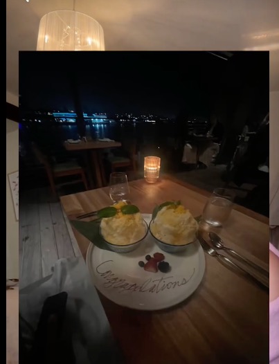 Dessert plate with "Congratulations" written in chocolate, two bowls of dessert, and berries at a night outdoor dining setting.