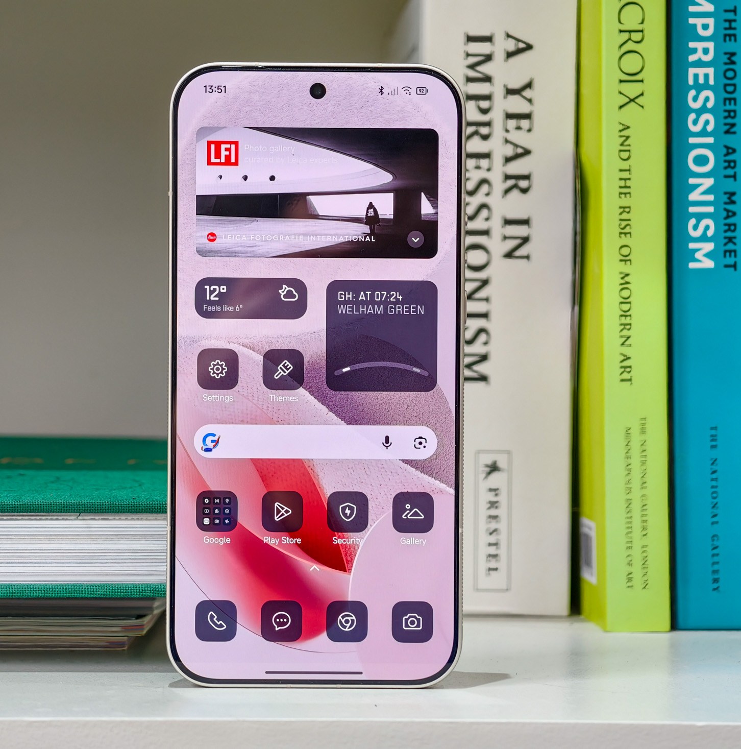 Photo of the Xiaomi Leica Leitzphone on a bookshelf, showing the home screen with monochrome widgets