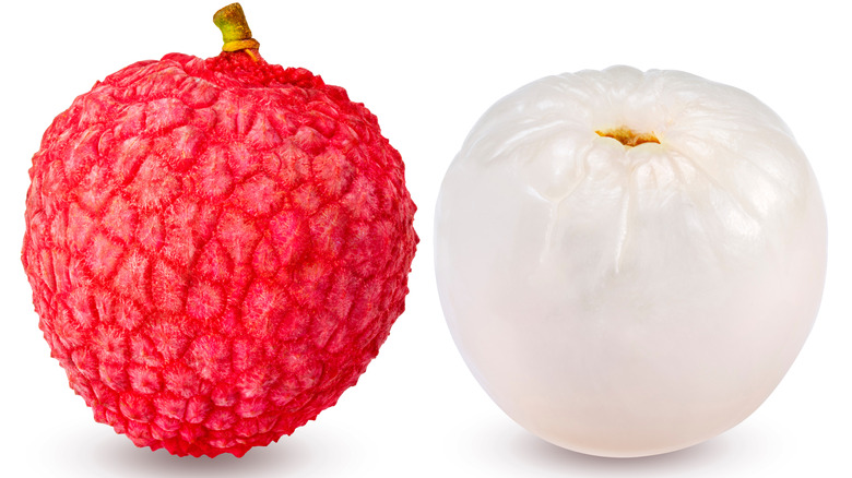 A whole and a peeled lychee on white background
