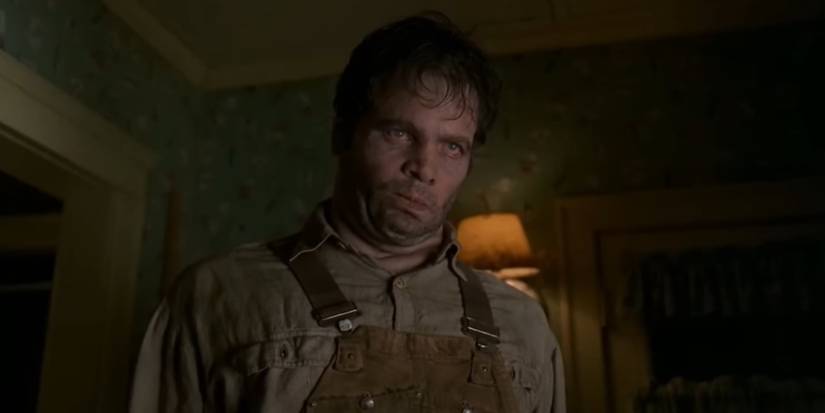 Edgar, played by actor Vincent D'Onofrio, standing limp and menacing in overalls in a house in Men in Black.