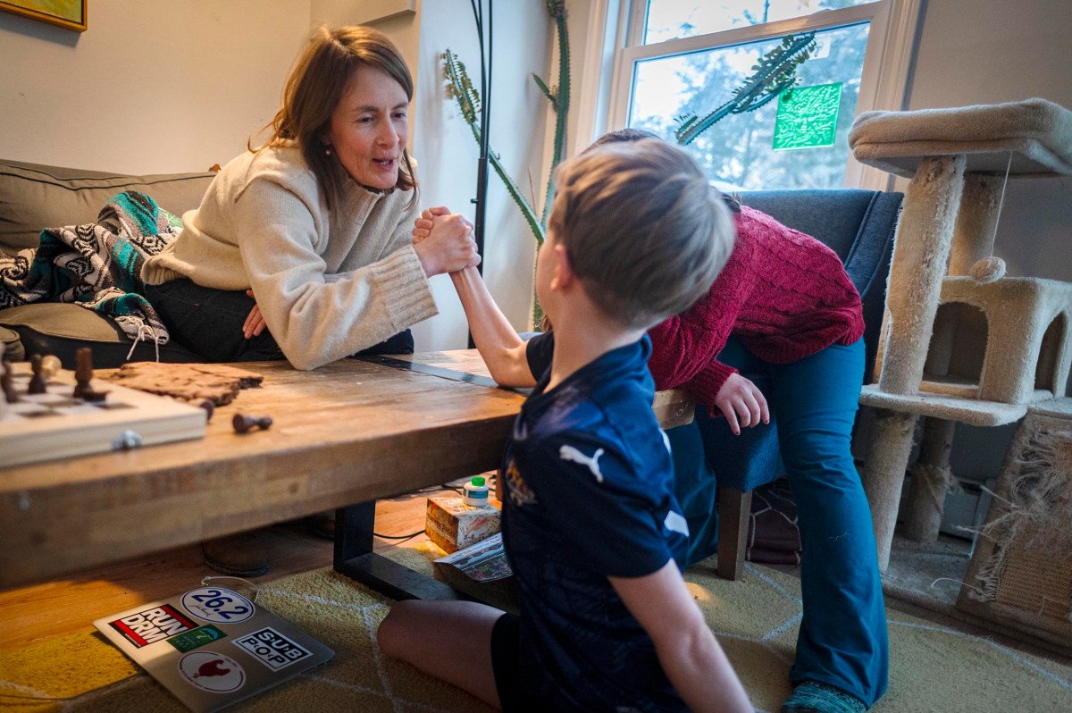A woman and boy arm wrestling.