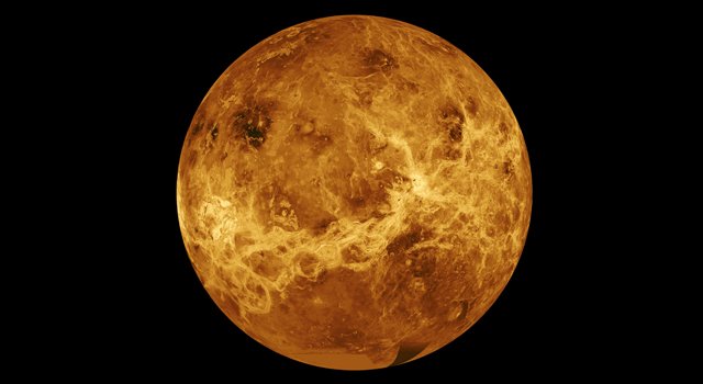 A close up of Venus in space, its golden surface glowing in the darkness